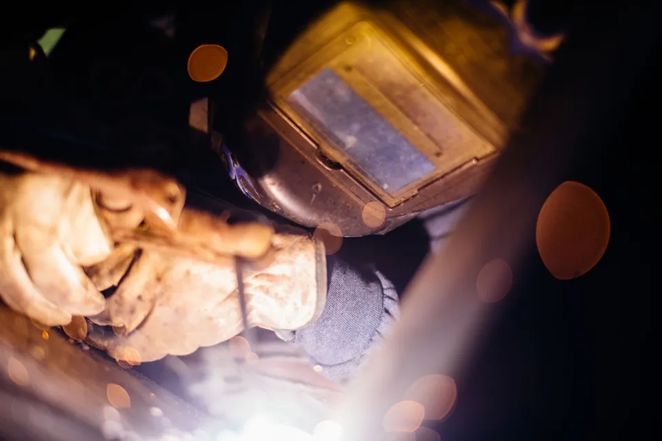 Soldador con casco y guantes trabajando entre chispas